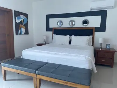 a bedroom with a large bed with a blue bench at Gaia Residence Deluxe in San Felipe de Puerto Plata
