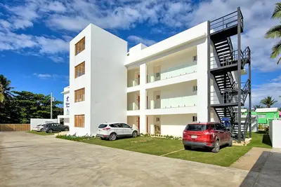 a white building with two cars parked in front of it at Amazing ocean view apartment with grand pool in Cabarete
