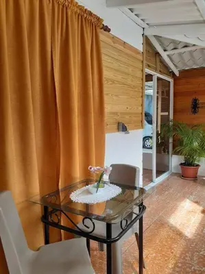 a glass table and chairs in a room with a curtain at Apartamento Hogareño in Jarabacoa
