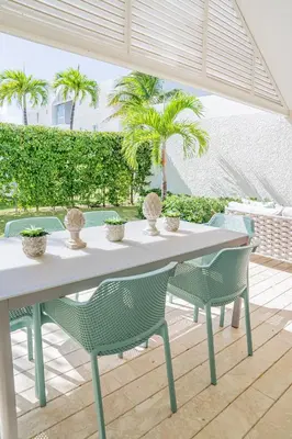 a table and chairs on a patio with palm trees at Xeliter Green One Playa Dorada in San Felipe de Puerto Plata