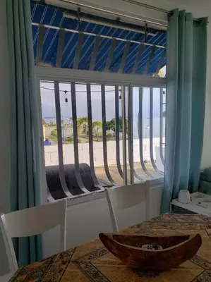 a room with a table and a window with a view of the beach at Indy's Best Bay FrontView in Samana. in Santa Bárbara de Samaná