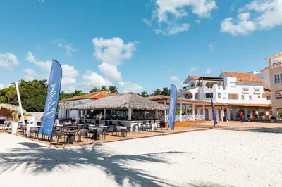 a patio with chairs and umbrellas on a beach at Hotel Palmera Bayahibe in Bayahibe