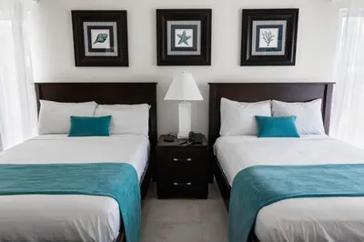 two beds in a hotel room with blue pillows at Hotel Palmera Bayahibe in Bayahibe