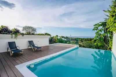 a swimming pool with two chairs on a wooden deck at Piece of Paradise in Las Terrenas