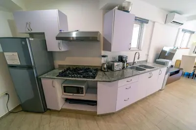 a kitchen with white cabinets and a stove and a refrigerator at Kite Beach Oceanfront 1st Row Two Bedrooms and patio in Cabarete