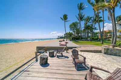 a wooden pathway to the beach with chairs and palm trees at Kite Beach Oceanfront 1st Row Two Bedrooms and patio in Cabarete