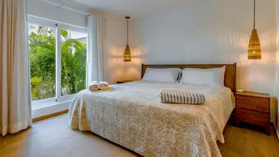 a bedroom with a bed and a large window at Kite Beach Oceanfront Two Bedroom Patio and Garden in Cabarete