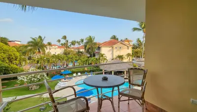 a balcony with a table and chairs and a view of a pool at Ocean Dream High Ceiling Studio w/balcony in Cabarete