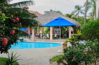 a blue umbrella next to a swimming pool at Ocean Dream top floor Studio with balcony in Cabarete
