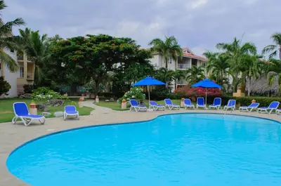 a large swimming pool with chairs and umbrellas at Ocean Dream top floor Studio with balcony in Cabarete