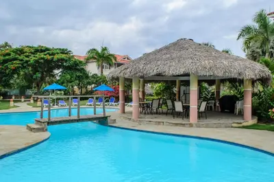 a resort with a swimming pool with a thatch roof at Ocean Dream top floor Studio with balcony in Cabarete