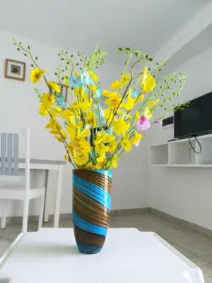 a colorful striped vase with yellow flowers on a table at Costarena Beach Hotel in Las Terrenas