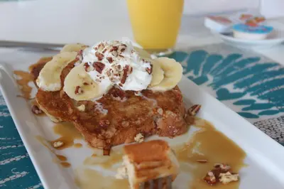 a plate of pancakes with bananas and whipped cream at Infiniti Blu Luxury Ocean Front Condos in Sosúa