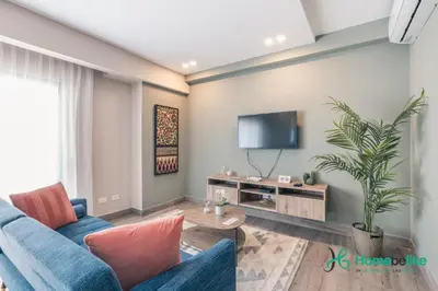 a living room with a blue couch and a tv at Chic Fully Serviced Apartment at Regatta Living II - 705 in Los Prados