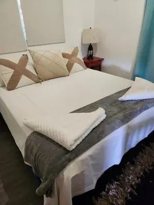 a bed with white sheets and pillows on it at Chalet los Pinos Constanza in Arroyo Frío