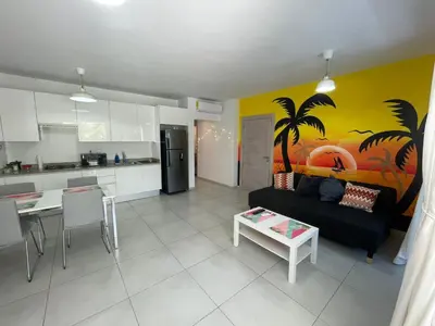 a living room with a black couch and a kitchen at Sunny garden in La Laguna