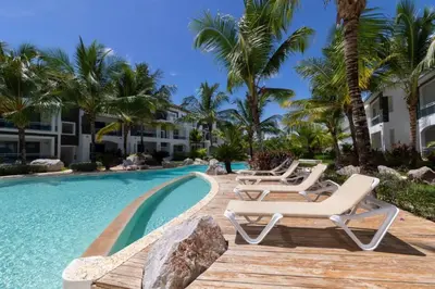 a resort pool with lounge chairs and palm trees at Sunny garden in La Laguna