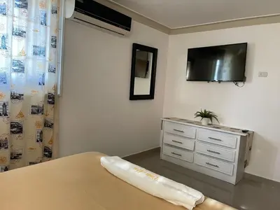 a bedroom with a dresser and a tv on the wall at Fully Equipped New 2br Apt-dt2mins To The Beach in Sosúa