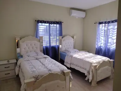two beds in a bedroom with blue curtains at Cabrera Family Villa in Cabrera