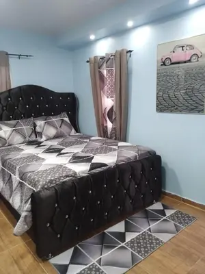 a black bed in a room with a picture of a pink car at Paulino in Santiago de los Caballeros