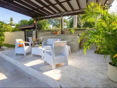 a patio with white chairs and tables and a brick wall at Cozy and Central apartment 1br-1ba with Pool in Sosúa