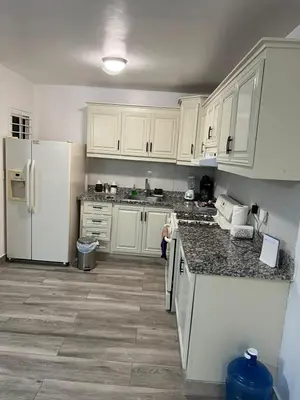 a kitchen with white cabinets and a white refrigerator at Escapade tropicale in Santiago de los Caballeros