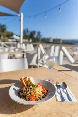 a plate of pasta on a table with a glass of wine at Room #27 at Waterfront Playa Alicia in Sosúa