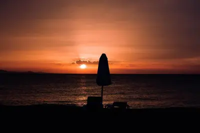 an umbrella and chairs on the beach at sunset at Room #27 at Waterfront Playa Alicia in Sosúa