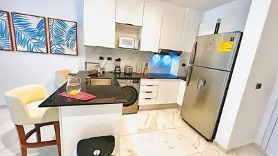 a kitchen with a refrigerator and a table with a wine glass at Hermoso Apartamento Cana Rock Star Acceso Directo a la Piscina C-105, C-106, B-102 y B-104 in Punta Cana