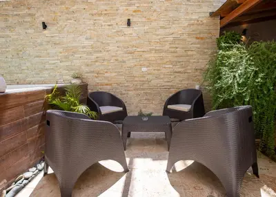a patio with chairs and a table and a brick wall at Central Area Bedroom With Common Kitchen, living room in Sosúa