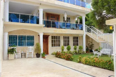 a house with a balcony and a patio at Central Area Bedroom With Common Kitchen, living room in Sosúa