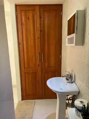 a bathroom with a sink and a wooden door at Central Area Bedroom With Common Kitchen, living room in Sosúa