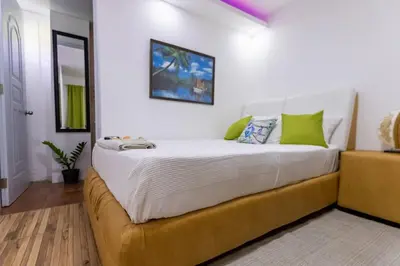 a bedroom with a large white bed with green pillows at Nice 1br-1bt With Common Picuzzi in Sosúa
