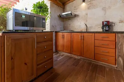 a kitchen with wooden cabinets and a microwave at Cozy 1bd with common Jacuzzi in Sosúa