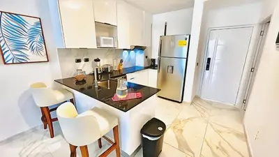 a kitchen with a black counter and a refrigerator at Cana Rock Star, Vista al campo de golf y Piscina C-303, B-400, B-506 y B-502 - Desayuno in Punta Cana