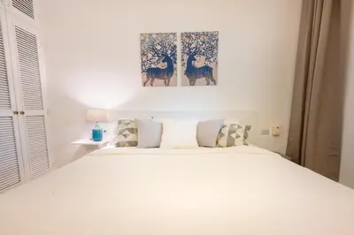 a bedroom with a white bed and a painting on the wall at Family Dominicus Apartment - Bayahibe in Bayahibe