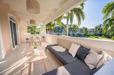 a living room with a couch on a balcony with palm trees at Family Dominicus Apartment - Bayahibe in Bayahibe