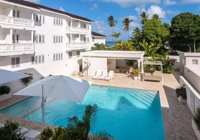a swimming pool in front of a building with an umbrella at Stella Aparthotel, Las Terrenas in Las Terrenas