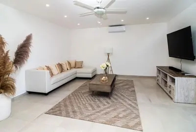 a white living room with a white couch and a flat screen tv at Stella Aparthotel, Las Terrenas in Las Terrenas