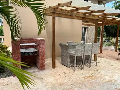 a patio with a grill and a wooden pergola at Villa 102A, 5 master bedroom and 5 full bathrooms with private pool in Sosúa