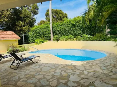 a swimming pool with two chairs next to a house at Hispaniola 3 bed, 3 bath Villa with pool & jacuzzi in Sosúa