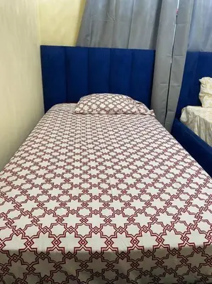 a bed in a room with a blue head board at Lesnah Apartamento, Jacobo Majluta in Los Casabes
