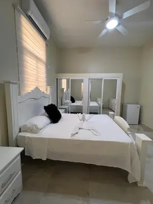 a bedroom with a large white bed with a ceiling fan at Hotel Unico in Santo Domingo