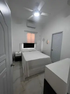 a white bedroom with a bed and a ceiling fan at Hotel Unico in Santo Domingo