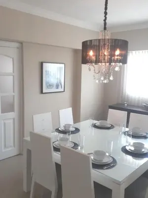 a white dining room table with white chairs and a chandelier at Cómodo y Equipado Apt Cerca del Malecón in Santo Domingo