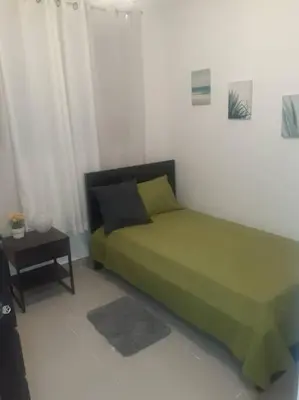 a bedroom with a green bed and a table at Comodas 3 Habitaciones, Wifi 1er piso in Santiago de los Caballeros