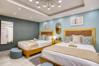 two beds in a bedroom with blue walls at Melina Hotel in Higuey