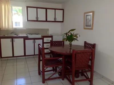 a kitchen with a wooden table and chairs and a table at La Punta Apartamentos in Cabarete