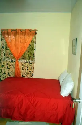 a bedroom with a red bed with an orange curtain at Alojamiento Wilkenia in Ochoa