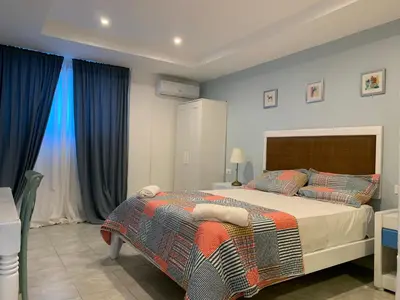 a bedroom with a large bed and blue curtains at Noé Hotel ,1 Bedroom # 5 near to the beach in Punta Cana